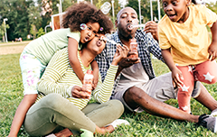 Family playing with bubbles outside on the grass.