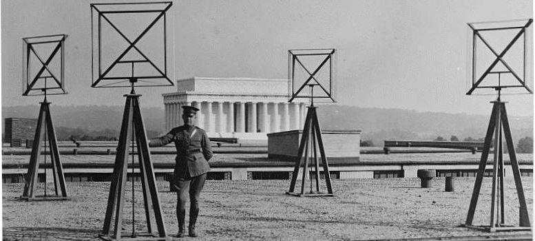 Image of a soldier standing next to radio antenna/satellite radars